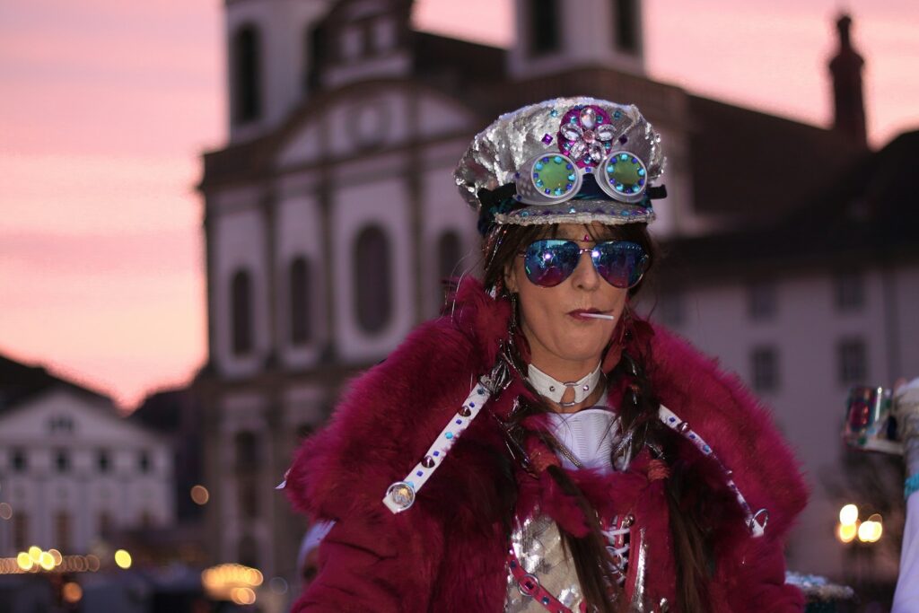 woman in purple fur coat wearing blue and green floral goggles